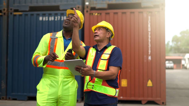 istock Logistic staff flying drone to survey and inspect stack container in shipment company area. 1462174015