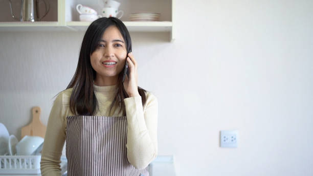 Woman using smart phone and drink coffee in kitchen room. stock photo