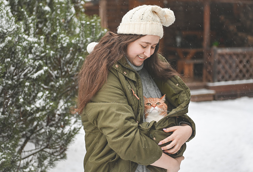 young woman with ginger cat outdoors in winter