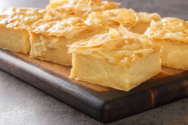 Delicious Greek sweet pastry Galaktoboureko, made of semolina custard in filo closeup on the wooden board. Horizontal Delicious Greek sweet pastry Galaktoboureko, made of semolina custard in filo closeup on the wooden board on the table. Horizontal filo pastry stock pictures, royalty-free photos & images