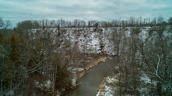 A Creek in a forested valley on a cloudy day in the winter. Taken with a drone from a bird's eye view.