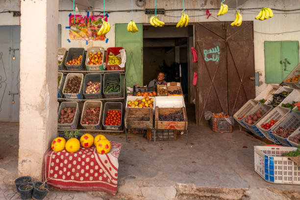 Small store with male vendor and merchandise (fruit, groceries)displayed in front of the shop in Boumalne Dades, Morocco