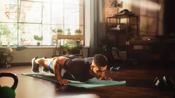 istock Strong Athletic Black Man Does Workout at Home Gym, Doing Push Ups. Lean Fit Muscular Mixed Race Sportsman Staying Healthy, Training at Home. Sweat and Determination. Wide Shot 1462191842