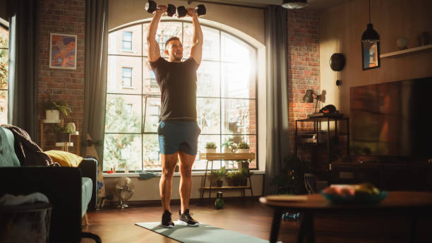 istock Strong Athletic Black Man Does Workout at Home, Single Leg Squatting with Dumbbell. Fit Muscular Sportsman Staying Healthy, Training Mind, Body. Sweat and Determination. Wide Angle Shot 1462191858
