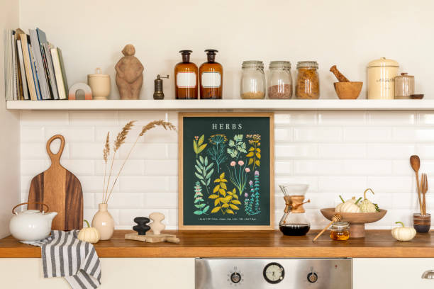 istock Creative composition of living room interior with mock up poster frame, vase with dried flowers, gray pitcher, jar with spices, bowl with vegetable and personal accessories. Home decor. Template. 1462192547