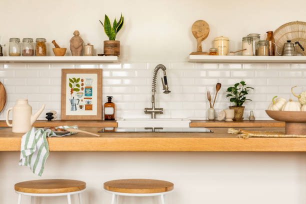istock Creative composition of kitchen interior with mock up poster frame, wooden kitchen island, simple barstool, silver tap, beige pitcher, vegetable and personal accessories. Home decor. Template. 1462192681