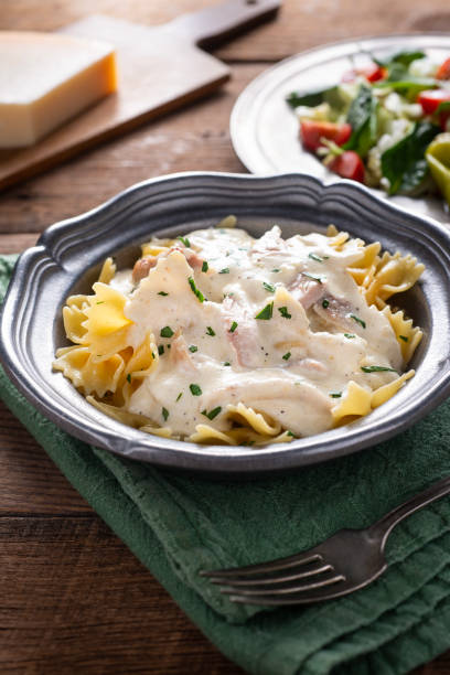 Pasta Alfredo Homemade Alfredo Sauce over Bow Tie (Farfalle) Pasta with Chicken cooked selective focus vertical pasta stock pictures, royalty-free photos & images