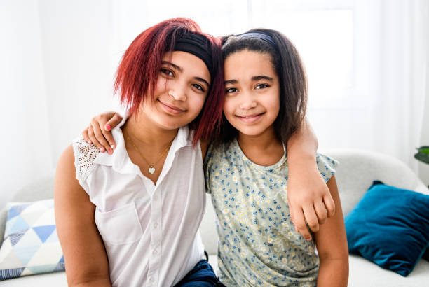 istock Two cute black sisters having great time on sofa at home 1462198486