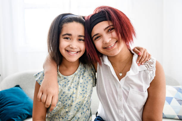 istock Two cute black sisters having great time on sofa at home 1462198498