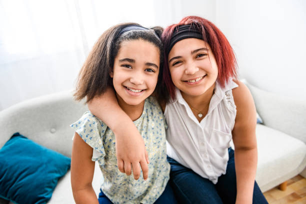 istock Two cute black sisters having great time on sofa at home 1462198506