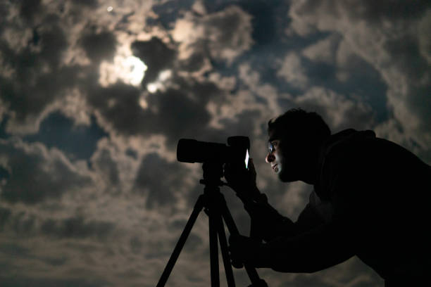 istock Man shooting the night cloudy sky under moon with a tripod 1462199756