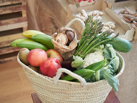 Wicker basket full of vegetables and fruits. Sustainable food shopping concept, plastic-free grocery store. Small local business.
