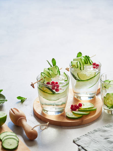 fresh infused cucumber water with lime, mint and red currants. Garnished with thin, wavy cucumber strips on a skewer.