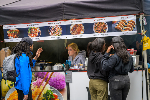 LONDON - May 20, 2022: Female serves customer at pop up street food stall on South Bank