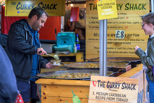 LONDON - May 20, 2022: Man serves customer curry at pop up street food stall on South Bank