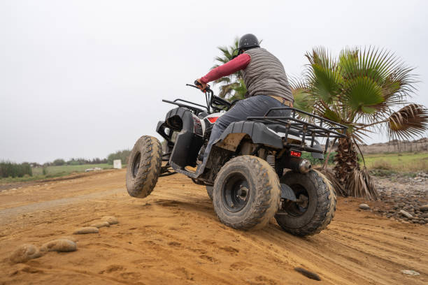 istock Man climbing a small hill on a quad bike 1462201042