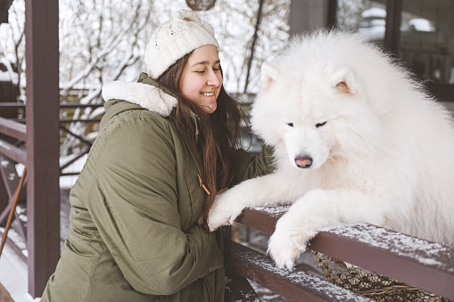 young woman with samoyed dog outdoors in winter