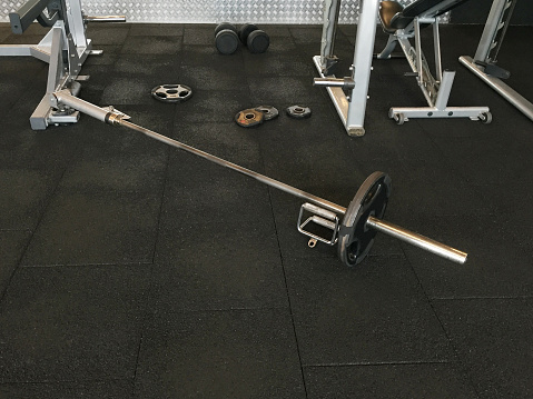 Fitness exercise equipments barbell, dumbbells and weights on rubber flooring in gym