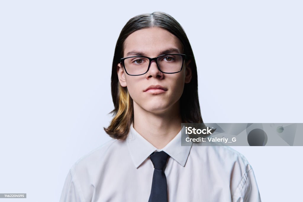 Headshot portrait of serious teenage guy on light studio background Headshot portrait of serious teenage guy 18, 19 years old, on light studio background. Confident handsome young male in glasses shirt and tie looking at camera, photo for documents, student ticket Photo Booth Picture Stock Photo
