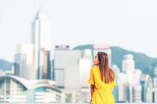 A woman enjoying the view of Hong Kong Island's cityscape from across the harbour.