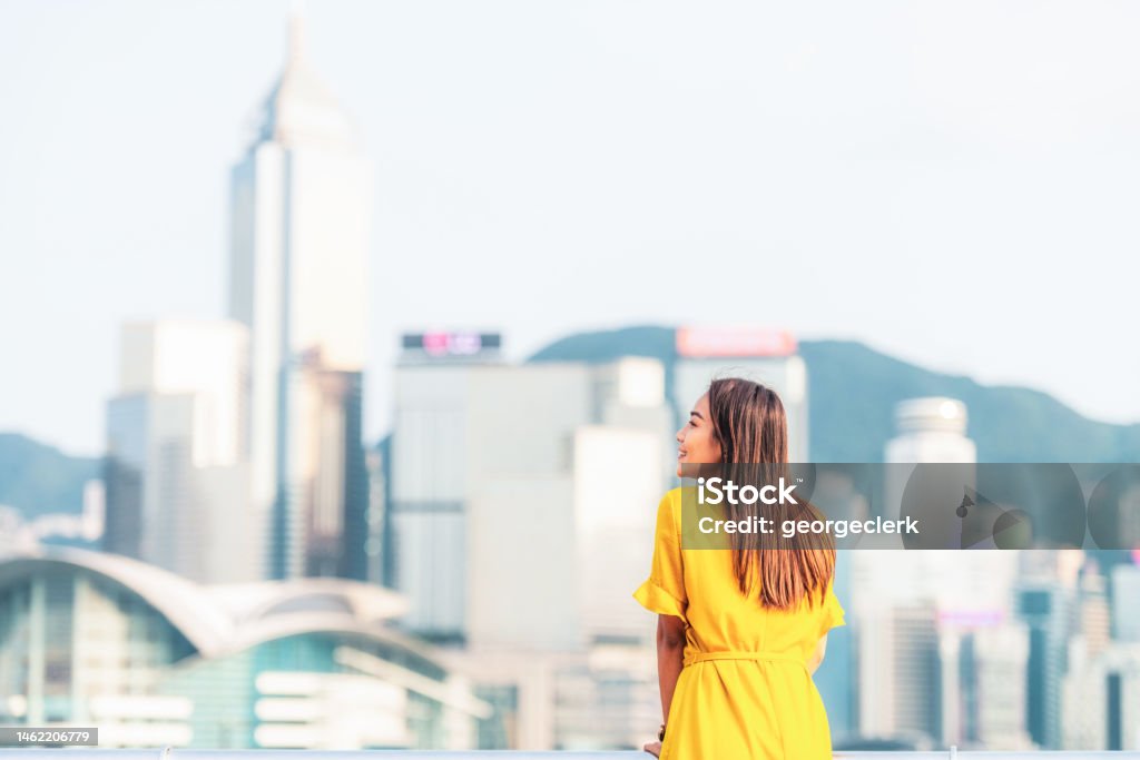 Visiting Hong Kong's Waterfront A woman enjoying the view of Hong Kong Island's cityscape from across the harbour. Hong Kong Stock Photo