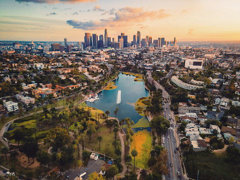 This is a drone photo taken from the above of the Echo Lake Park during sunset, showing the lake and the skyline of DTLA