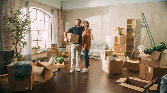 Family New Home Moving in: Happy and Excited Young Couple Enter Newly Purchased Apartment. Beautiful Family Happily Embracing, Imagining Future. Modern Home Ready for Decorations