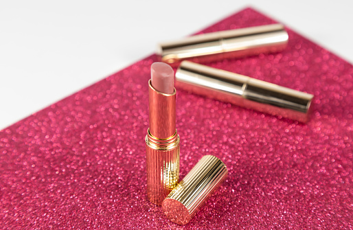 Lipstick in a gold tube of nude color on the makeup table
