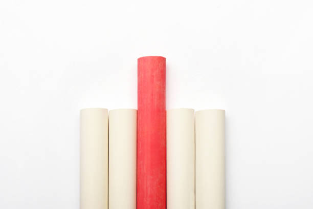 Leadership education concept. A red chalk among white chalks on the white background