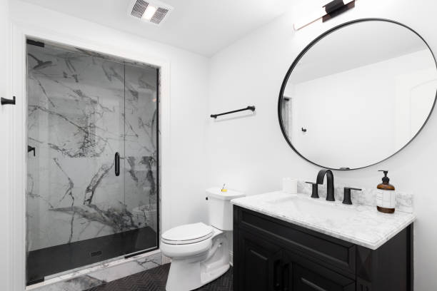 istock A bathroom with a black cabinet, circular mirror, and marble shower. 1462211460