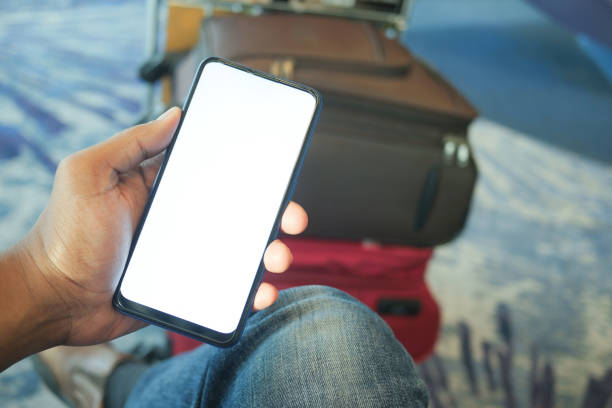 istock holding smart phone with empty screen and stack of Suitcases at airport 1462214474
