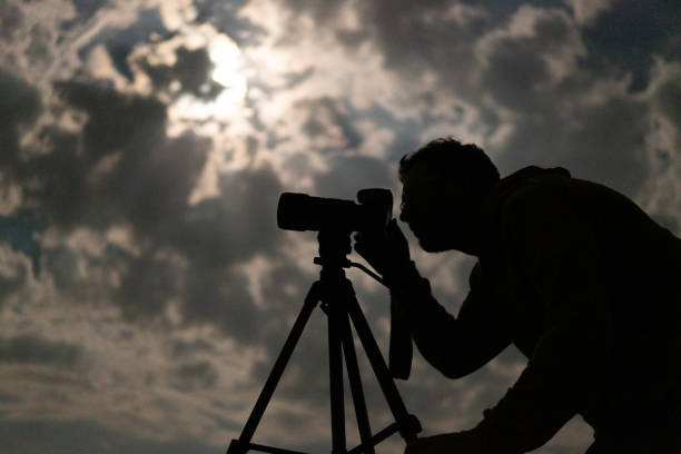 istock Man shooting the night cloudy sky under moon with a tripod 1462218867