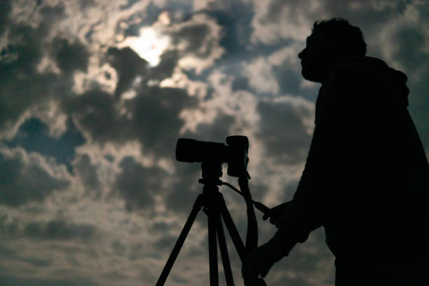 istock Man shooting the night cloudy sky under moon with a tripod 1462218874