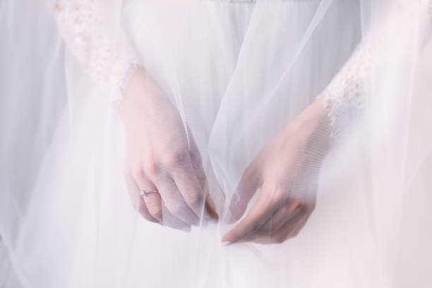 istock Bride hand with a beautiful diamond ring on a white dress covered with a veil 1462221741