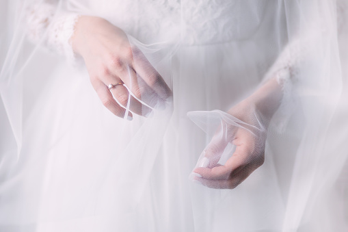Preparativos de bodas. Manos de la novia con una manicura cuidada con un hermoso anillo en el vestido. photo