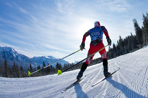 A man competes in a cross-country ski race at the Canmore Nordic Centre Provincial Park in Alberta, Canada. He is doing the skate-ski technique.