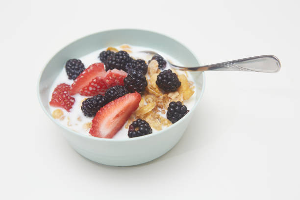 Cereal and strawberries in an orange bowl on a yellow background with copy space.