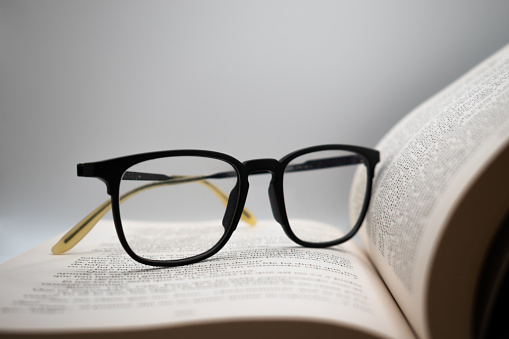 Glasses and open book on grayish background