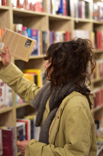 Young woman in a bookstore choosing a book to read next being serious and curious