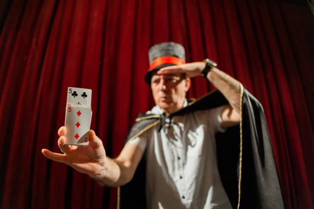 istock Senior magician doing magic trick with playing cards on the stage 1462257501