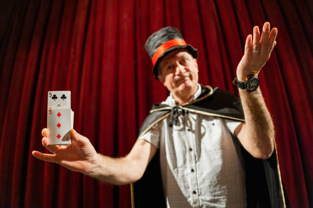 istock Senior magician doing magic trick with playing cards on the stage 1462258050
