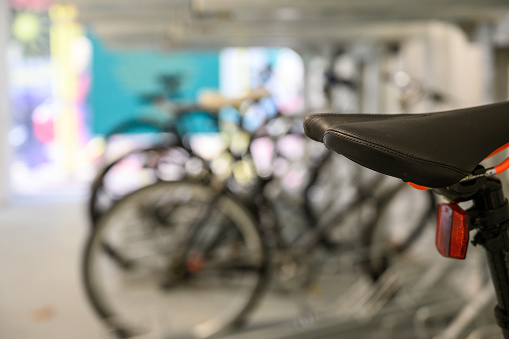 Close up of bicycle saddle with bikes out of focus in the background.