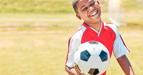 Happy, soccer and child on sport field with soccer ball excited for training, game or competition with smile. Black kid, football and health of young athlete on grass ready to play match for fitness.