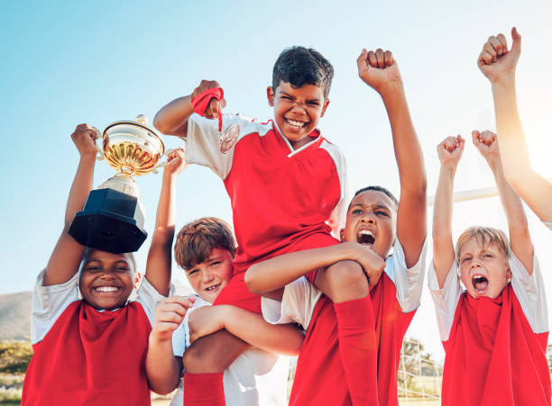 soccer, celebration and kids team with trophy on soccer field, happy and excited at winning game. sports, boy children goal and success in teamwork at football with gold medal award with winner smile - soccer celebration success group of people imagens e fotografias de stock