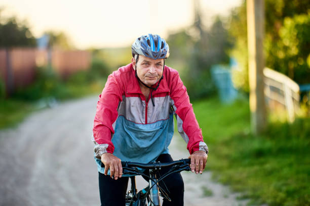 夏の夜に田舎で60歳以上のサイクリスト。 - cycling senior adult sports helmet men ストックフォトと画像