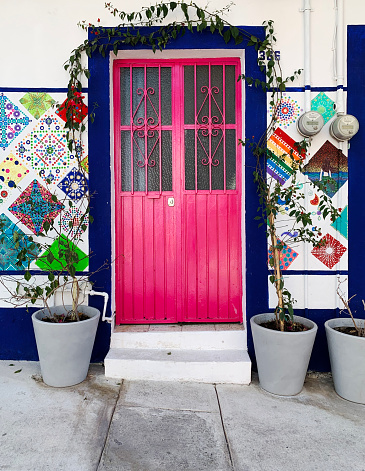 Puerto Vallarta Mexico — January 15, 2023: A colorfully painted door and wall in Mexico. Doors and windows in the area behind the Parroquia de Nuestra Señora de Guadalupe cathedral are often painted in decorative colors to suit the owners’ desires.