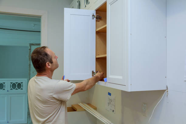 In a new home, a carpenter is fixing a door to a kitchen cabinet In new home carpenter is fixing door to kitchen cabinet kitchen cabinet refacing stock pictures, royalty-free photos & images