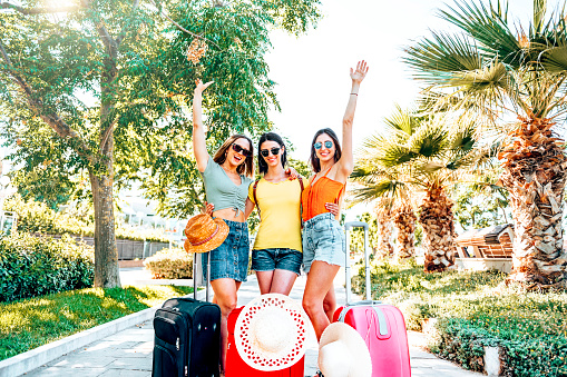 Young friends girls with suitcase excited about their new trip having fun near airport  - Female people with their luggage enjoy travel together - Trip life style concept with young people relaxing