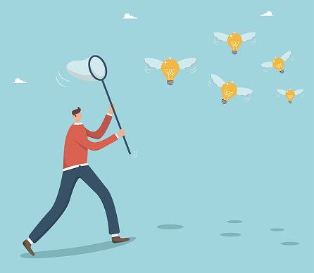 Create new business ideas and projects with creativity and leadership, brainstorm, achieve goals. Catch your luck. Businessman chasing ideas, catching flying light bulbs with a butterfly net.