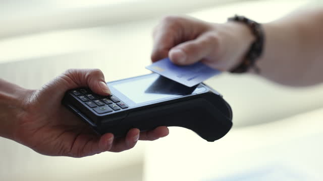 Client makes payment applies card to terminal cashier machine, closeup